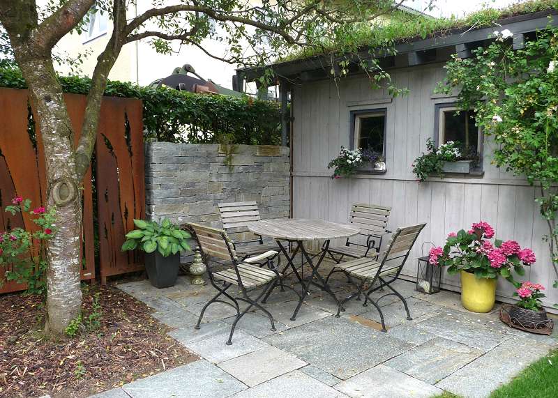 Granitstein-Terrasse mit Gartenmöbeln in einem Privatgarten